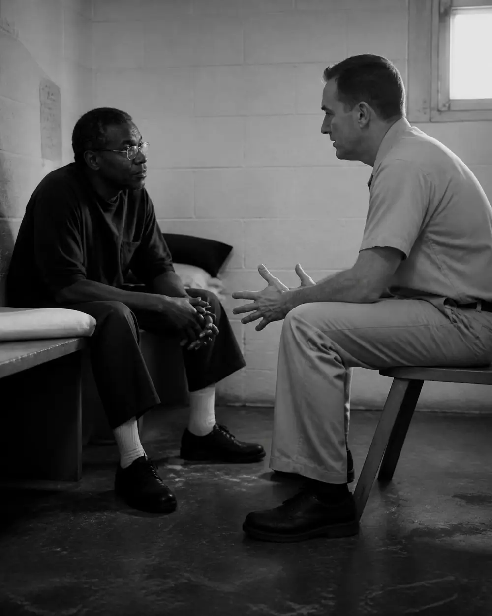 Dos hombres conversando sentados dentro de un centro de reclusión